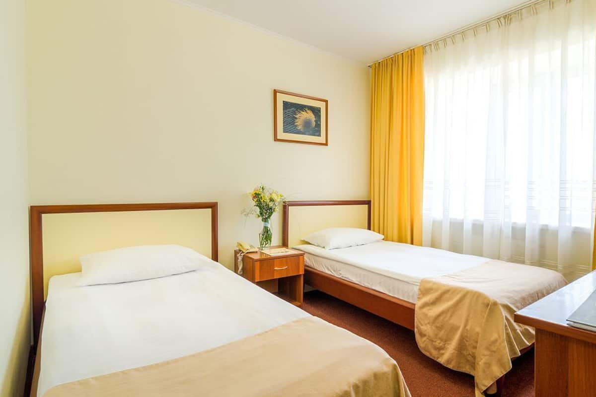 Ein Hotelzimmer mit zwei Betten, einem Schreibtisch, einem Sessel, einem Fernseher und einem Fenster mit Vorhängen.