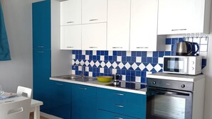 A modern kitchen with white and blue cabinets, a microwave, and an oven.
