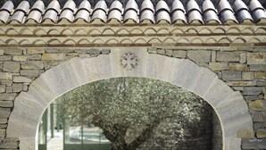 Una estructura de piedra arqueada con un árbol en el centro, rodeada por un muro de piedra y un techo de tejas.