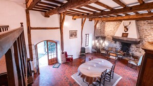 A rustic dining area with a stone fireplace, wooden beams, and a view of the outdoors. - Clos Saint Michel - Pool - Nature and Calm (Saint-Michel-de-Vax)