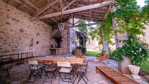 An outdoor patio with stone walls, wooden tables and chairs, and a hanging lantern. - Clos Saint Michel - Pool - Nature and Calm (Saint-Michel-de-Vax)