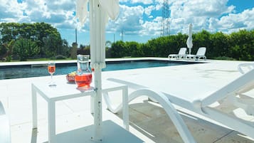 Relax by the pool surrounded by lush greenery and lounge chairs.