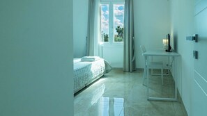 Un dormitorio moderno con una cama, una mesita y un escritorio con lámpara.