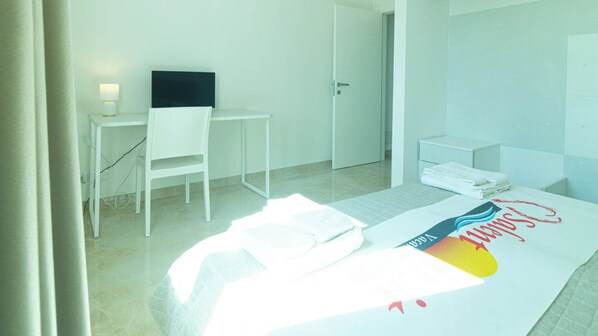Une chambre d’hôtel avec un lit, un bureau, une chaise et une porte.