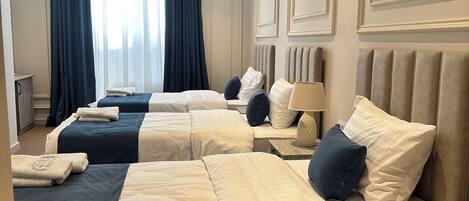 Una habitación de hotel con tres camas, cada una con cabecero, mesitas de noche y lámpara.