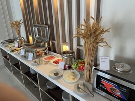 A buffet setup with various food items and a Samsung refrigerator.