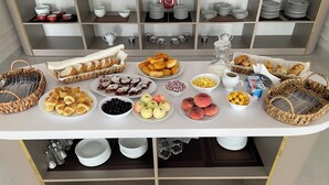 Monipuolinen aamiaisbuffet, jossa on tarjolla erilaisia leivonnaisia, hedelmiä ja juomia.