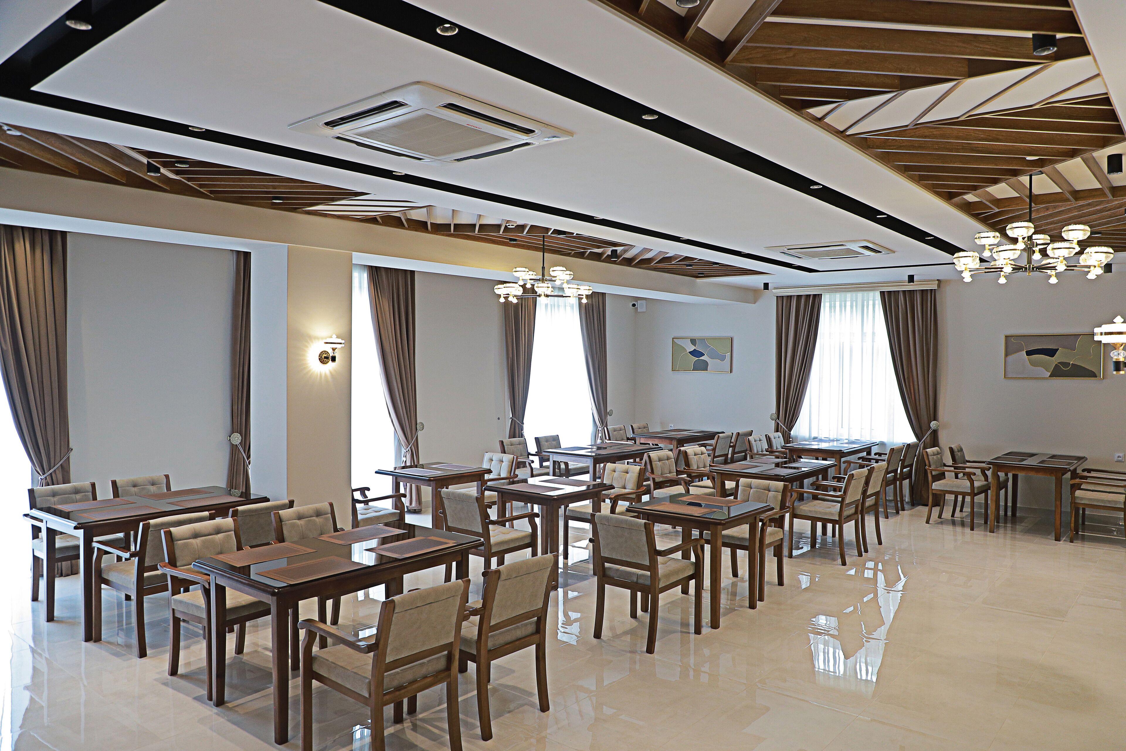 A spacious dining area with multiple tables and chairs, a chandelier, and a polished floor.