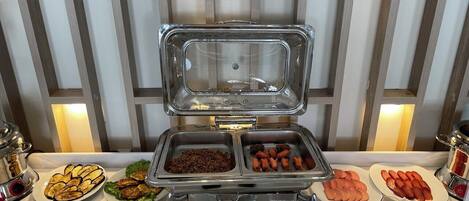 A buffet setup with various food items and utensils.