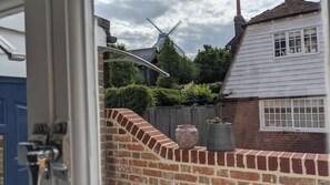 Experience the charm of a traditional windmill in a serene rural setting, surrounded by lush greenery and historic village architecture.