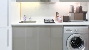 A compact kitchen with a built-in gas stove, a sink, and a front-loading washing machine. - Urban Charm: Studio With Balcony in Azizi Riviera (Dubai)
