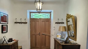 A hallway with a wooden door, a rug, a desk with a lamp, and a mirror on the wall. - Maison Play (Roumoules)