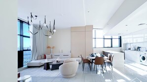 A modern living room with a sofa, coffee table, and dining area. - Stylish 1BR With Balcony City Views O2 Tower, JVC (Dubai)