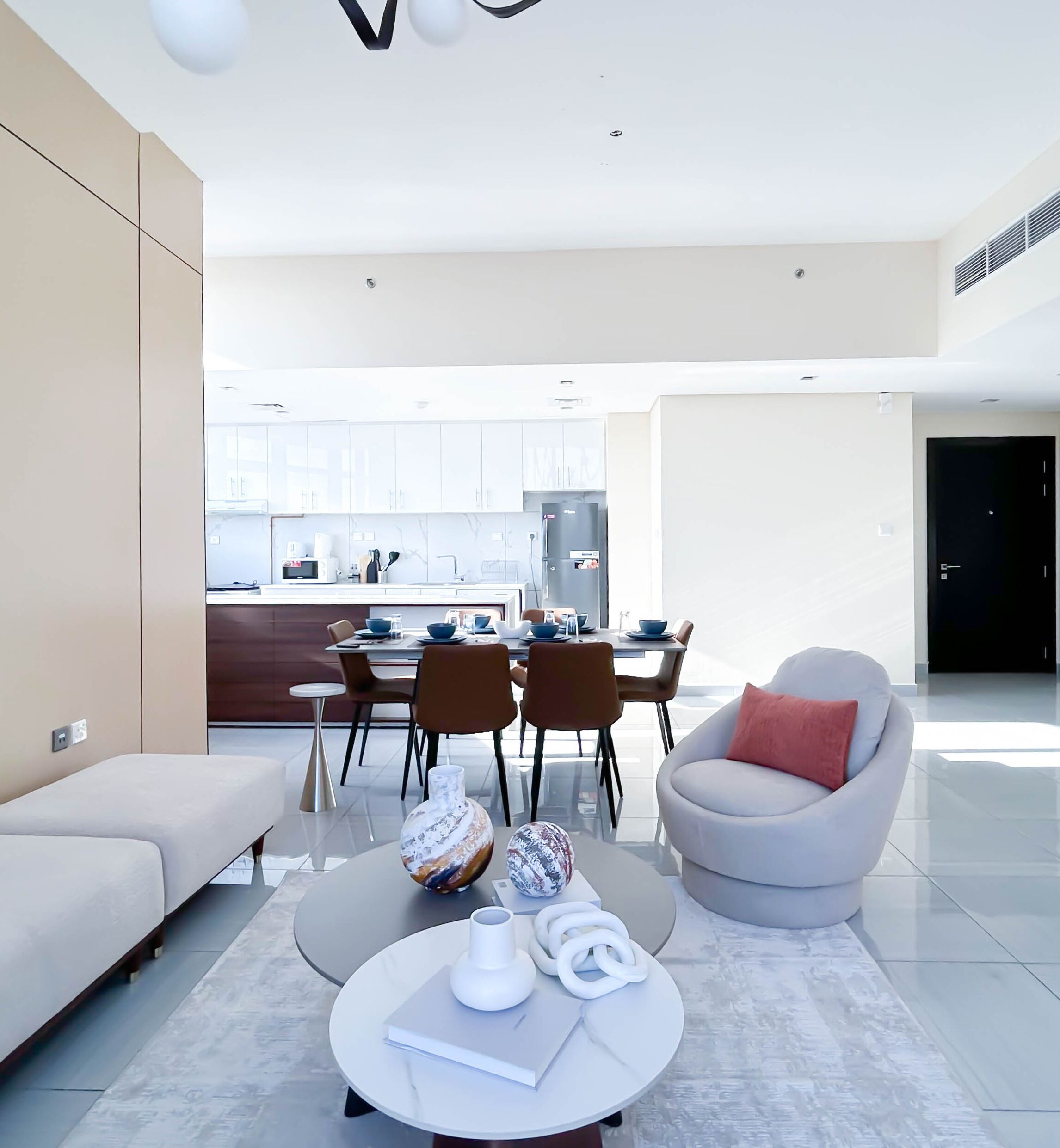A modern living room with a sofa, a coffee table, and a dining area with chairs and a table.
