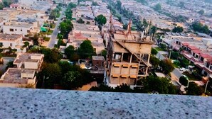 Un paisaje urbano con un edificio destacado que tiene una azotea con múltiples antenas.