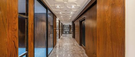 Un pasillo con paneles de madera, suelo de mármol y techo decorativo.