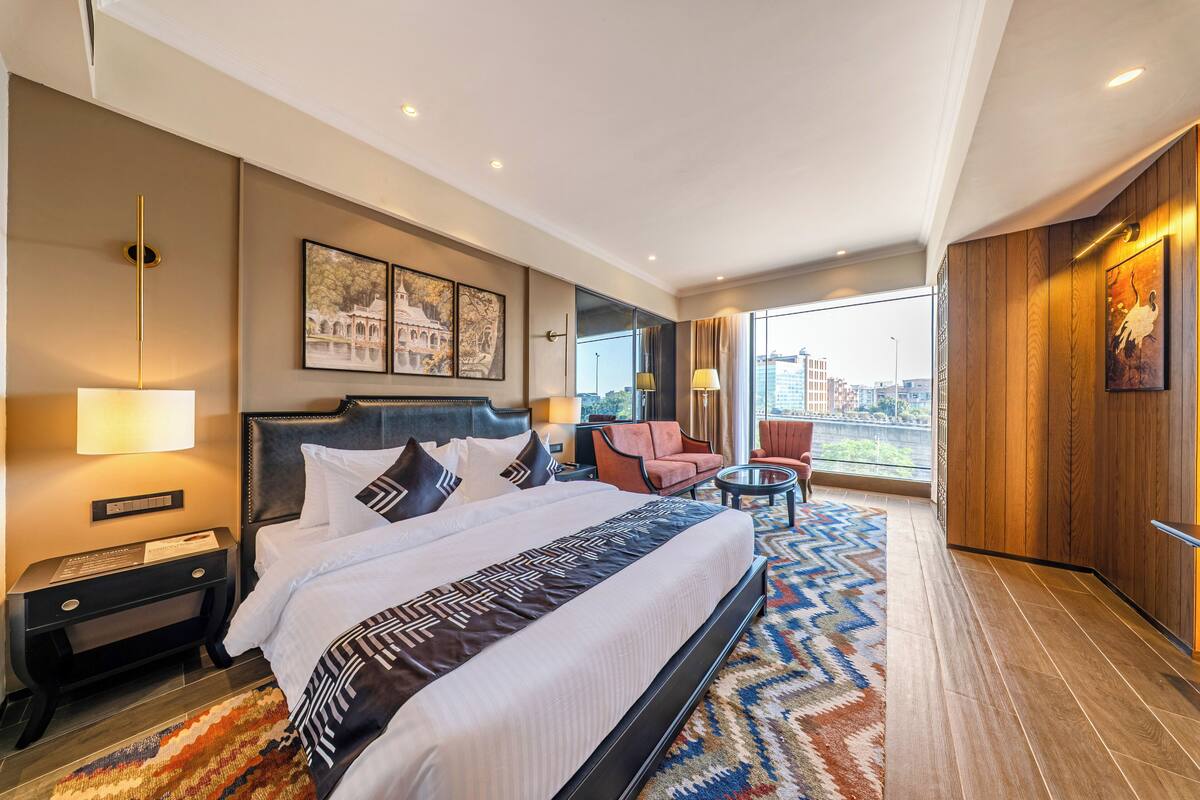 Une chambre d’hôtel moderne, dotée d’un grand lit, d’un bureau, d’une chaise et offrant une vue sur la ville.