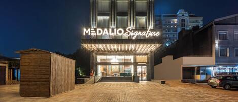 A modern building with a sign reading "MEDALIO Signature" at night.