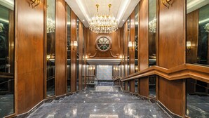 Eine prächtige, polierte Marmortreppe mit Holzvertäfelung und einem großen Chandelier an der Spitze.