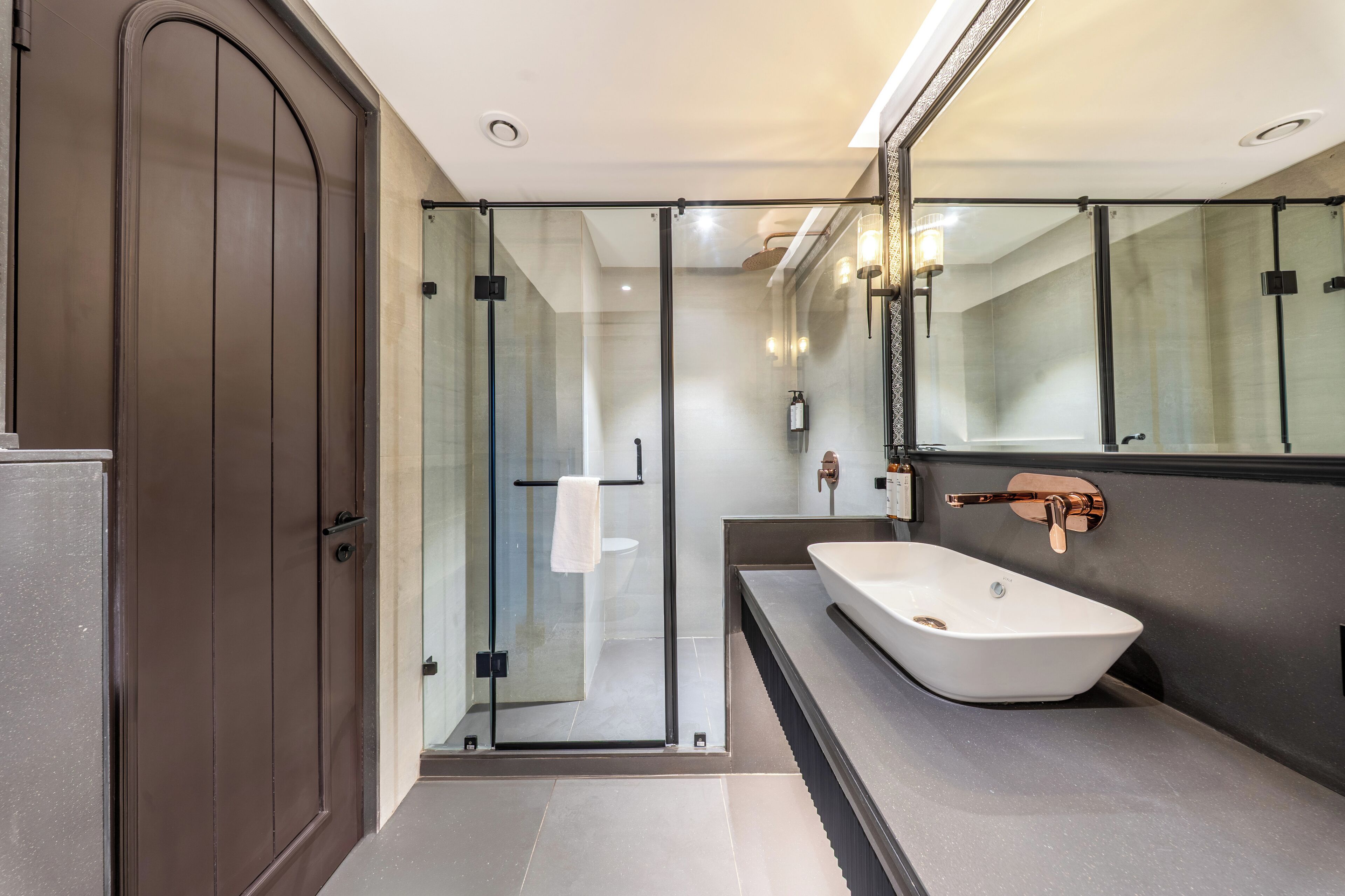 A modern bathroom with a glass-enclosed shower, a large mirror, and a white vessel sink.