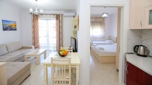 A modern hotel room with a sofa, dining table, and a bed. - Seascape Sea view Apartment (Vlorë)