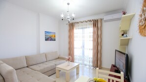 A living room with a beige sofa, a wooden coffee table, a TV, and a fruit bowl. - Seascape Sea view Apartment (Vlorë)