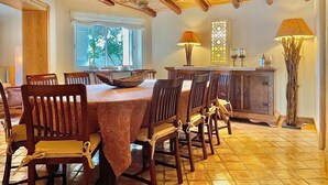 A dining area with a wooden table and chairs, a decorative lamp, and a window with blinds.