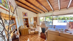 A spacious living area with a thatched roof, a poolside seating area, and a view of the pool.