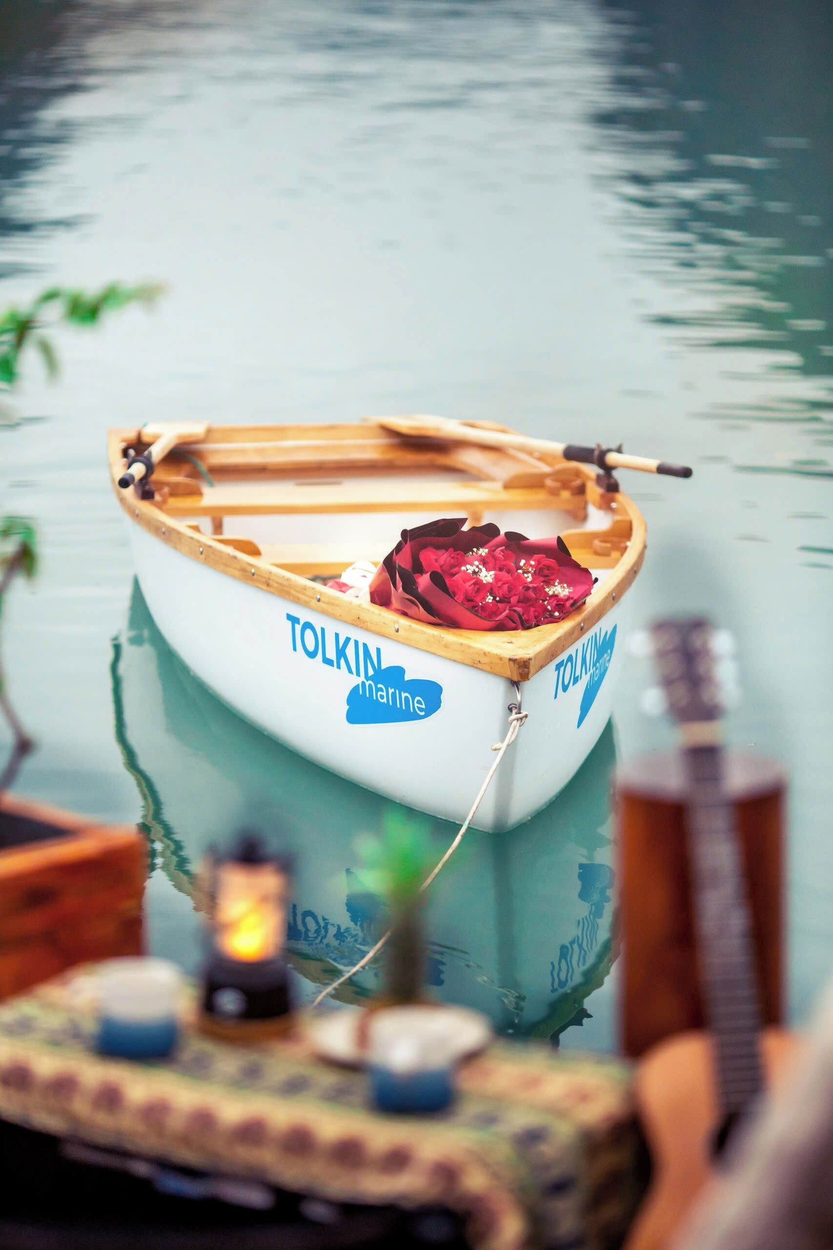 A small wooden boat with the name "TOLKIN marine" on its side, floating on calm water.