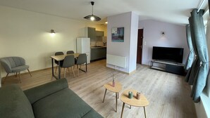 Un salon moderne comprenant un canapé, un coin repas avec des chaises, une cuisine et un téléviseur.