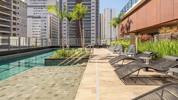 Zona de piscina en la azotea con sillones de descanso y vistas despejadas de edificios altos aledaños.
