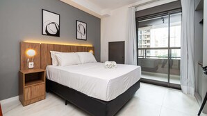 Un dormitorio moderno con cama, mesitas de noche y un ventanal con vistas.