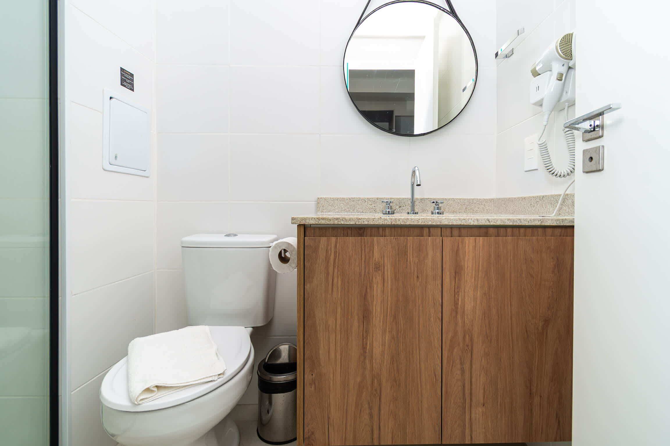 Ein Badezimmer mit Toilette, einem Holzschrank, einem Spiegel und einem Fön.