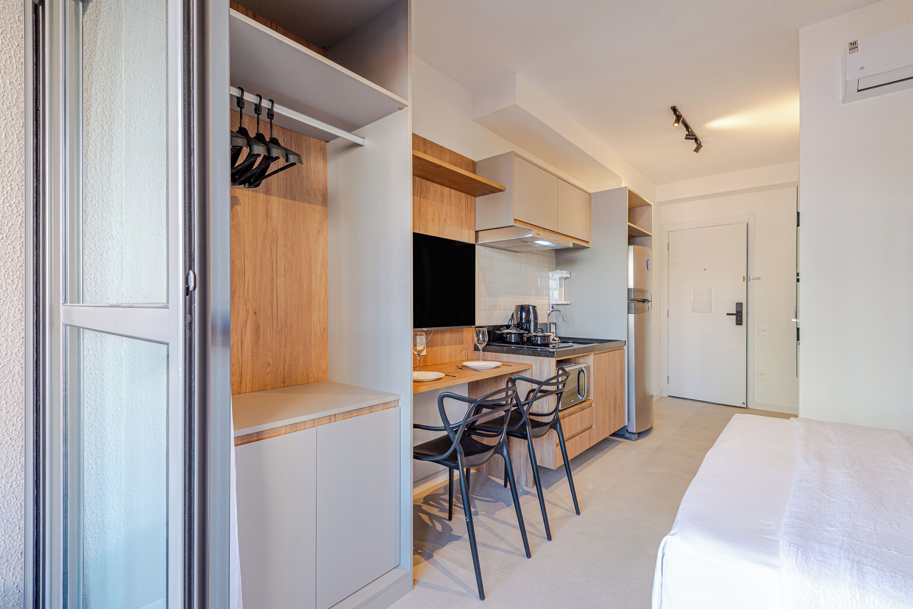 A compact kitchen with modern appliances, a dining area with a table and chairs, and a separate bedroom with a bed.