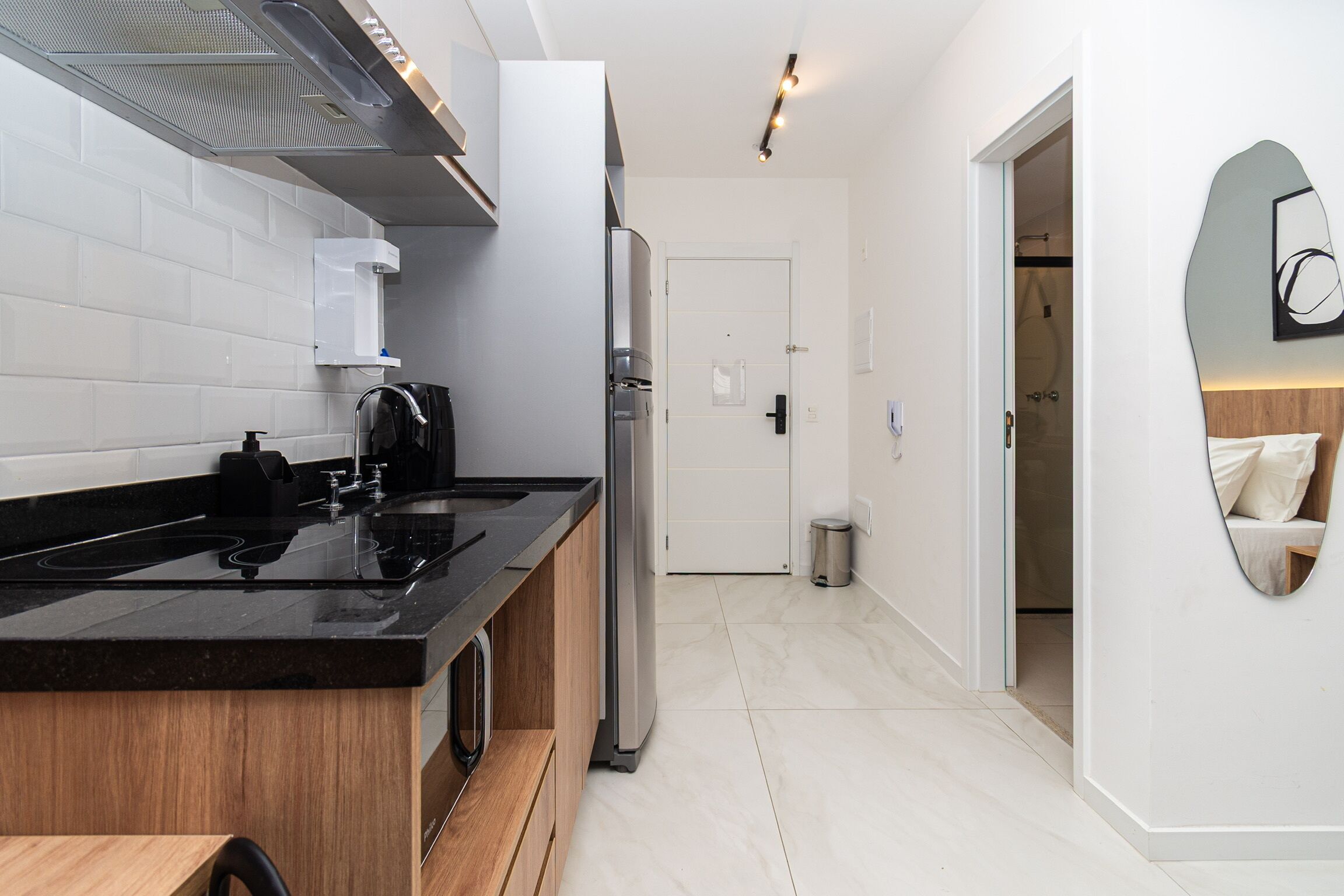 A modern kitchen with a black countertop, stainless steel appliances, and a white tiled backsplash.