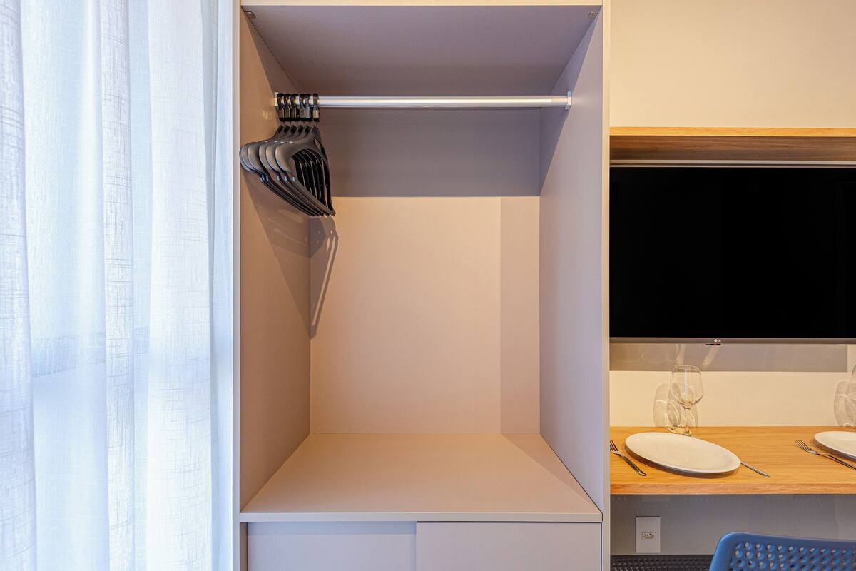 Ein Hotelzimmer mit einem Bett, einem Nachttisch, einem Fernseher und einem Fenster mit Vorhängen.