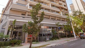 Un edificio residencial de varios pisos con balcones, un acceso con portón y un área de estacionamiento pequeña.