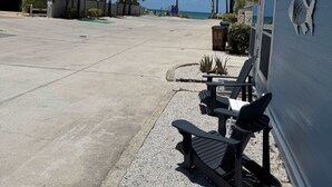 A beachfront property with a patio area featuring outdoor seating, palm trees, and a view of the ocean. - Beach House Cottage Pool Spa on Beach Access (Indian Rocks Beach)