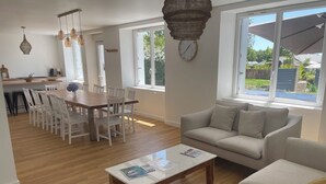 A modern living room with a sofa, a coffee table, and a dining area with chairs and a table. - New, seaside house, Beg meil, for groups and families  (Fouesnant)