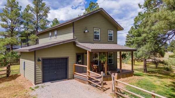 A two-story house with a covered porch, a garage, and a fenced yard.