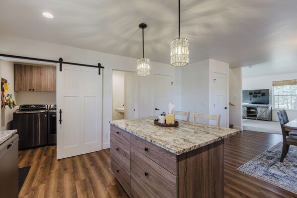 A modern kitchen with a central island, wooden cabinets, and stainless steel appliances.