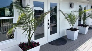 A modern house with a white exterior, large glass doors, and potted plants on the porch. - 3+ BR Beach ViewHouse (Palm Coast)