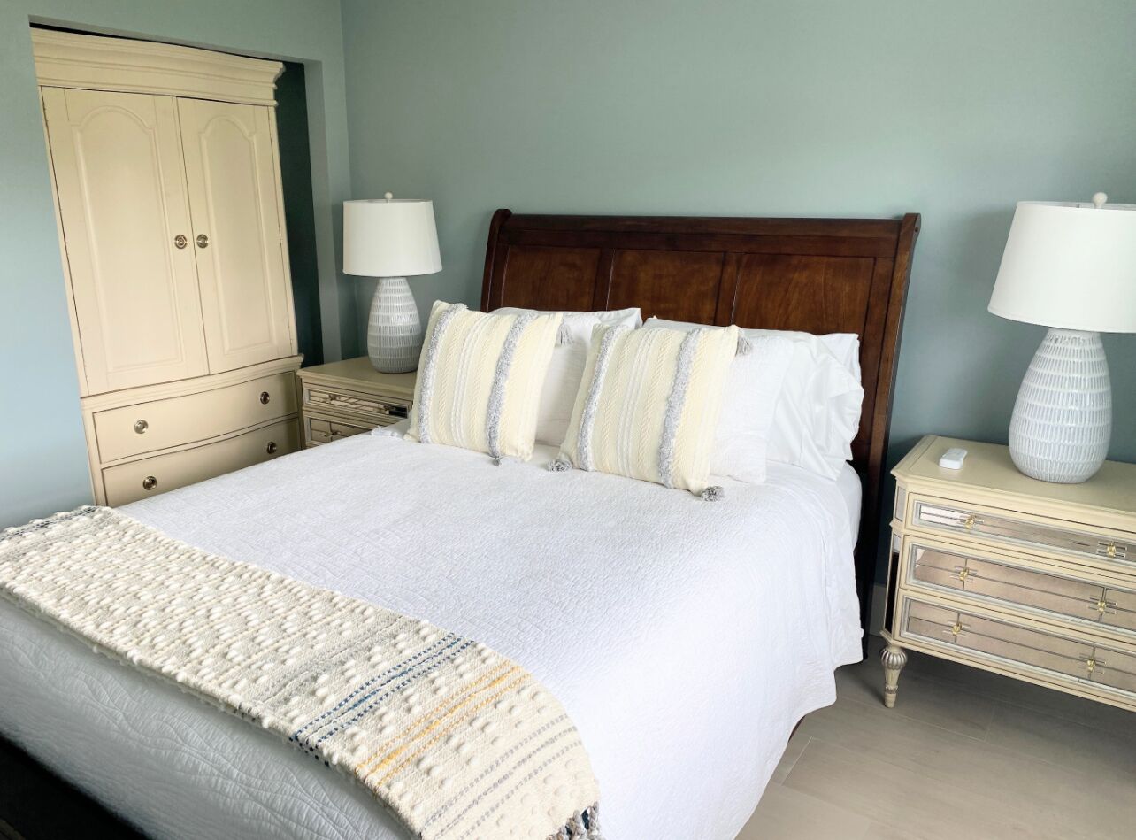 Une chambre à coucher avec un grand lit, deux tables de chevet, une armoire et une lampe de chaque côté du lit.