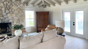 A spacious living room with a stone fireplace, a large window, and a ceiling fan. - 3+ BR Beach ViewHouse (Palm Coast)
