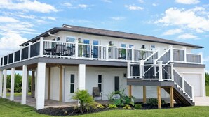 A two-story house with a covered patio and a staircase leading to a deck. - 3+ BR Beach ViewHouse (Palm Coast)
