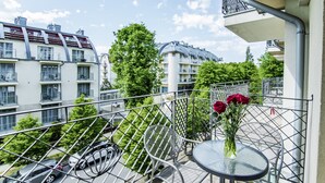 Un balcon avec une balustrade en métal, une petite table ronde et un vase rempli de fleurs.