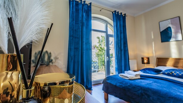 Une chambre à coucher avec un lit, une fenêtre avec des rideaux, une lampe et un tableau au mur.