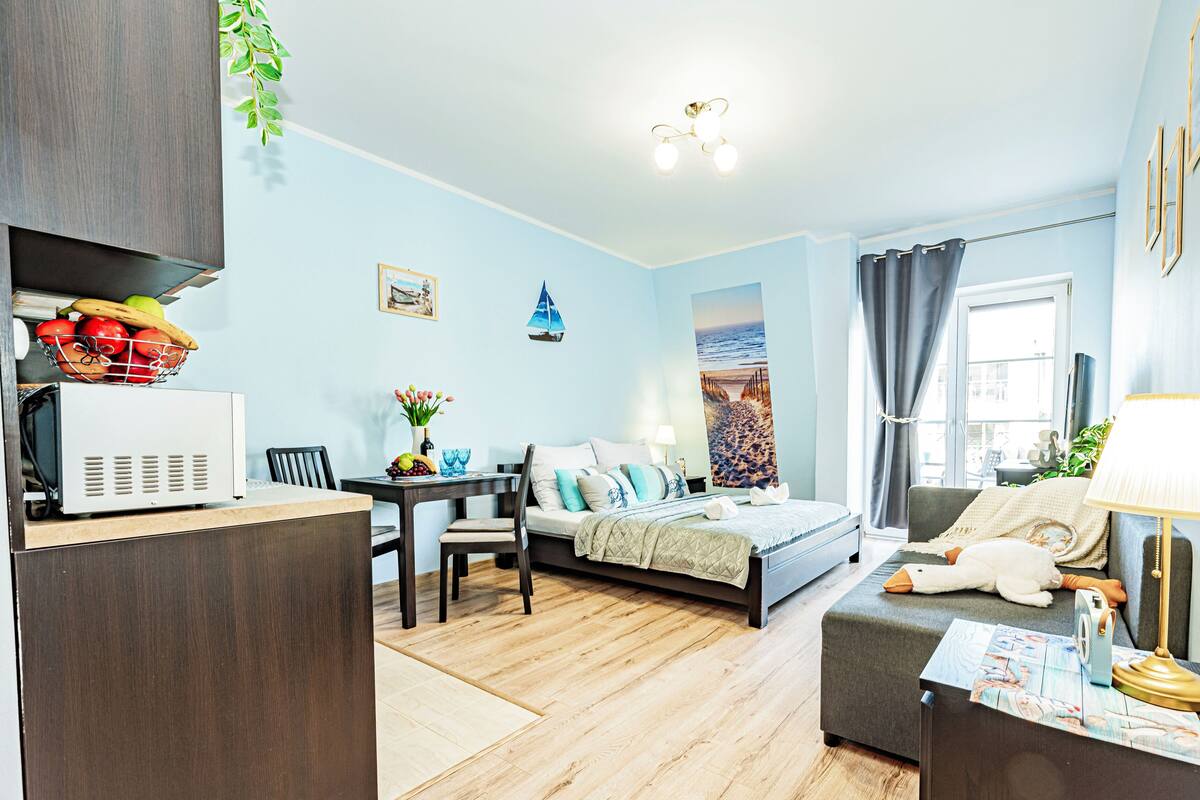 Una habitación de hotel compacta con cama, escritorio, zona de comedor y kitchenette.