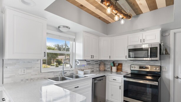 A modern kitchen with white cabinetry, stainless steel appliances, and a large island. - Christmas vacation time in Crystal River! Waterfront Pool home. Manatee season!! (Crystal River)