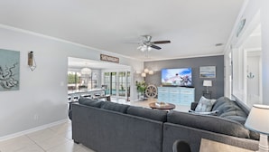 A modern living room with a sectional sofa, a television, and a ceiling fan. - Christmas vacation time in Crystal River! Waterfront Pool home. Manatee season!! (Crystal River)